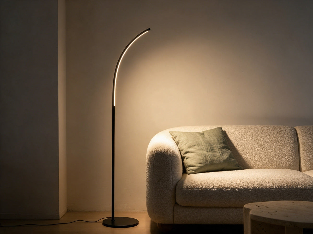 Calira Bogen-Stehleuchte neben einem Boucle-Sofa, schlanker hoher Bogen mit Lichtlinie auf der Innenseite